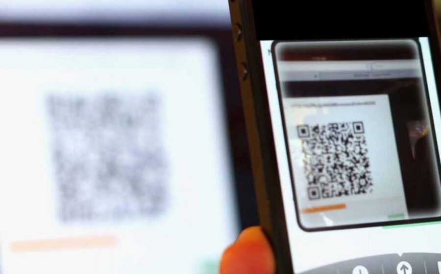 Pessoa escaneando QR Code adulterado com smartphone em restaurante, golpe do Pix