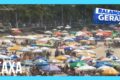 Placa de sinalização da Taxa de Preservação Ambiental na entrada de Guarujá com praia ao fundo