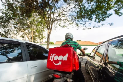Logos do iFood e Keeta em confronto com símbolos de dinheiro e balança da justiça
