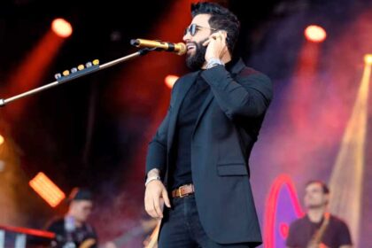 Gusttavo Lima no palco durante show de réveillon com microfone em destaque