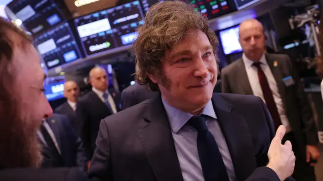 Javier Milei em pronunciamento oficial com símbolo da criptomoeda LIBRA e balança da justiça ao fundo