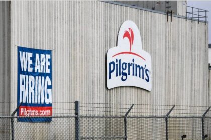 Logotipo da JBS e Pilgrim's Pride sobre fundo de fábrica de processamento de carne, simbolizando aquisição