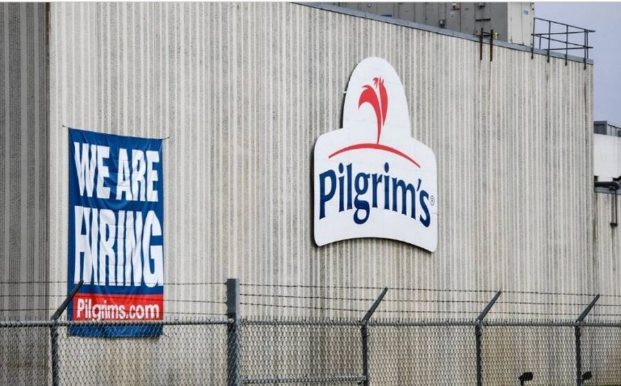 Logotipo da JBS e Pilgrim's Pride sobre fundo de fábrica de processamento de carne, simbolizando aquisição