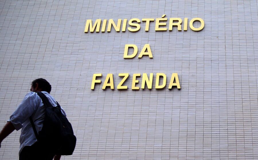 Gráfico de juros altos com silhueta do Ministério da Fazenda ao fundo, simbolizando política monetária rígida