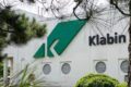 Gráfico de ações KLBN11 em queda com ícone de custo industrial em destaque
