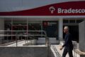 Sede do Bradesco com gráfico de lucro crescente e indicador de inadimplência em alta
