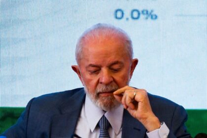 Lula e Flávio Bolsonaro em debate presidencial com fundo do TSE