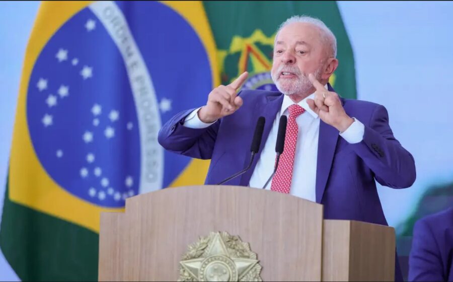 Lula discursa após vitória eleitoral com logos de Big Techs ao fundo simbolizando regulação