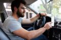 Motorista de aplicativo dirigindo carro à noite, simbolizando vulnerabilidade e insegurança no trabalho