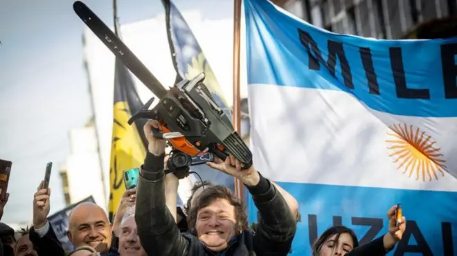 Javier Milei com motosserra simbólica cercado por prédios públicos argentinos