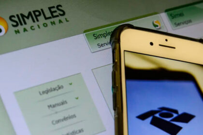 Empresário emitindo nota fiscal única federal no computador, com tela mostrando sistema da Receita Federal para Simples Nacional