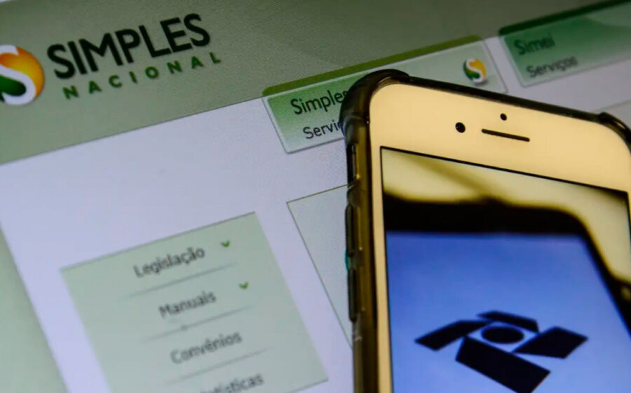 Empresário emitindo nota fiscal única federal no computador, com tela mostrando sistema da Receita Federal para Simples Nacional