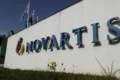 Sede da Novartis em Basileia com gráficos financeiros sobrepostos simbolizando prejuízo contábil e alta no lucro operacional
