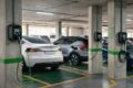Carregador veicular elétrico instalado em garagem de condomínio com sinalização de segurança