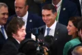 Tesoura cortando documento orçamentário com bandeira do Brasil ao fundo, simbolizando corte de gastos públicos