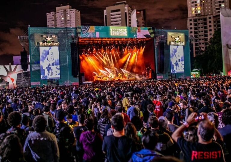 Multidão em festival de música com gráficos de finanças pessoais sobrepostos mostrando endividamento