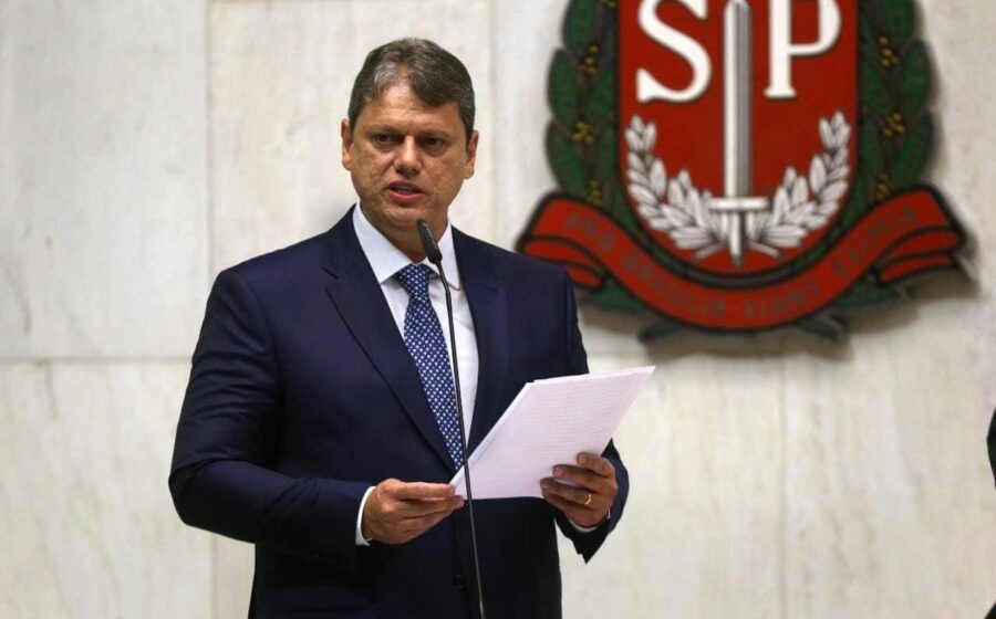 Governador segurando celular diante de rodovia esburacada e obras paralisadas