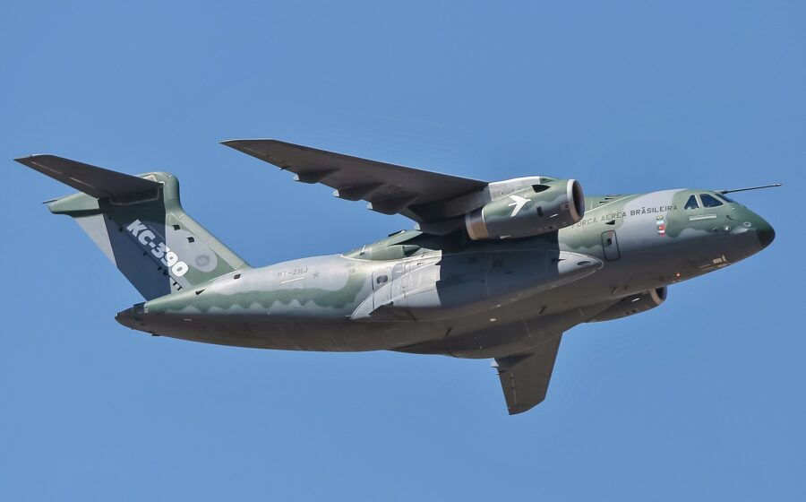 Jato militar Embraer C-390 Millennium voando com bandeiras do Brasil e Índia ao fundo
