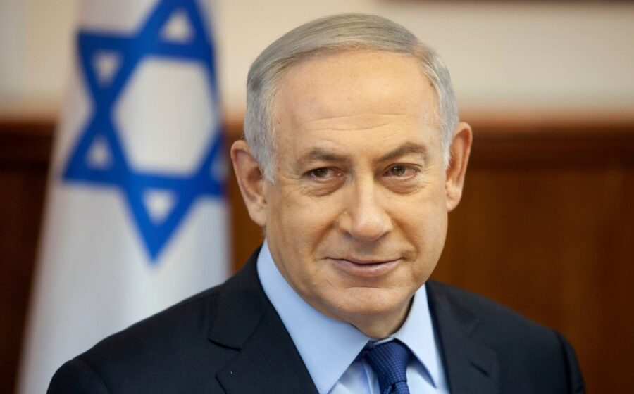 Benjamin Netanyahu discursando com gráficos de blockchain e símbolos de sanções bancárias ao fundo