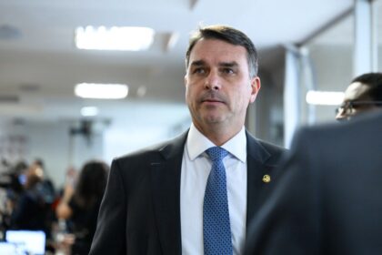 Senador Flávio Bolsonaro em retrato oficial, simbolizando investigações sobre alianças políticas, milícias e apostas online