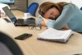 Pessoa trabalhando em home office com postura inadequada em mesa improvisada, notebook e cadeira comum