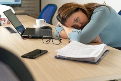 Pessoa trabalhando em home office com postura inadequada em mesa improvisada, notebook e cadeira comum
