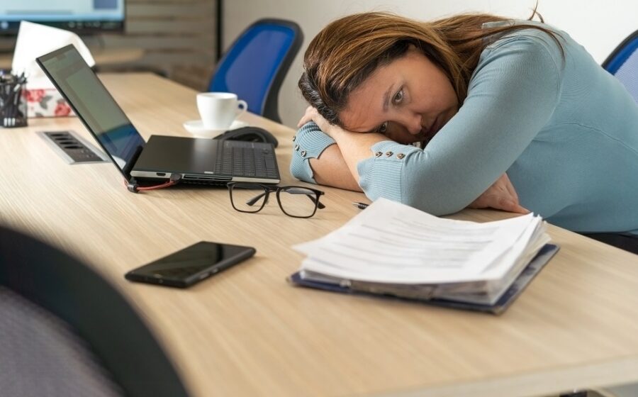Pessoa trabalhando em home office com postura inadequada em mesa improvisada, notebook e cadeira comum