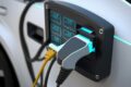 Carros elétricos carregando em estação pública com gráficos de crescimento de vendas ao fundo