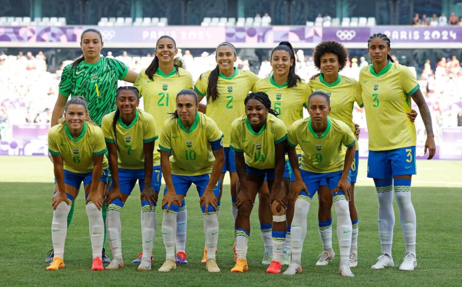 Três jovens jogadoras de futebol feminino sorrindo no Museu do Futebol em São Paulo