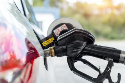 Bomba de diesel vermelho em posto com caminhão abastecendo, símbolo da nova ordem executiva de Trump