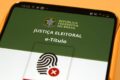 Rosana Magalhães criadora do e-Título segurando smartphone com aplicativo aberto