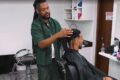 Empreendedor afro aplicando prótese capilar em cliente no estúdio especializado