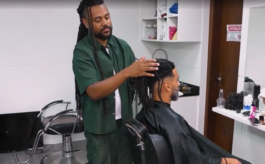 Empreendedor afro aplicando prótese capilar em cliente no estúdio especializado