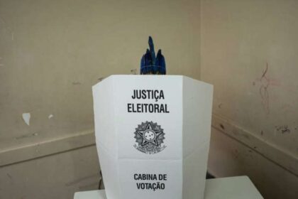 Urna eletrônica em seção eleitoral de Santa Catarina com mesários durante apuração pausada das eleições presidenciais