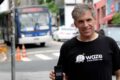 Uri Levine, cofundador do Waze, sorri em evento no Brasil com bandeira brasileira ao fundo