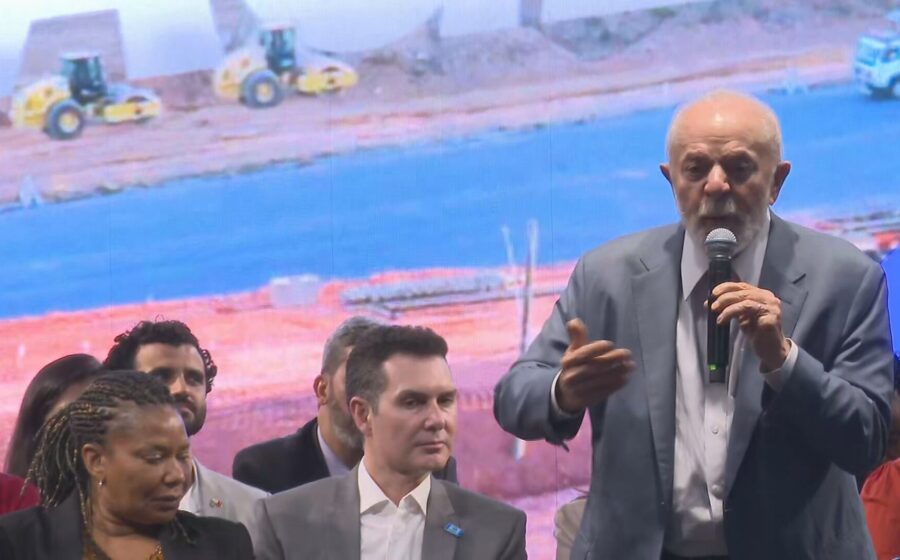 Lula discursa com gráficos de dívida pública e juros ao fundo