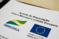 Eleitores diversos unidos diante de urna eletrônica com bandeira do Brasil ao fundo
