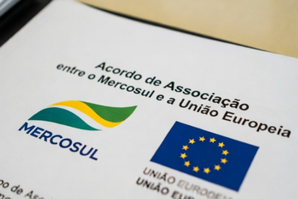 Eleitores diversos unidos diante de urna eletrônica com bandeira do Brasil ao fundo