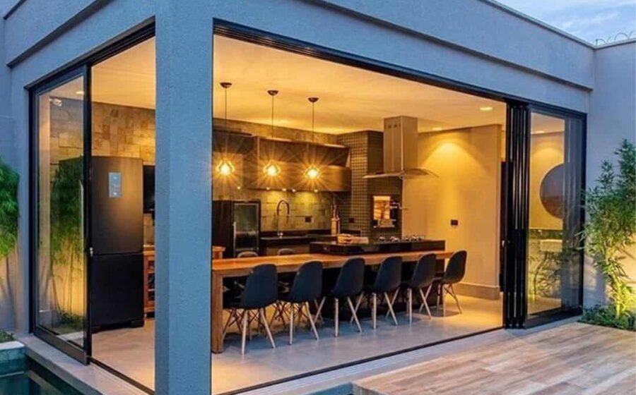 Área gourmet integrada à sala com bancada, cozinha e varanda em fluxo contínuo