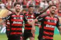 Flávio Bolsonaro ao celular com escudo do Flamengo e fichas de aposta ao fundo