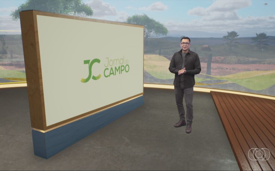 Apresentador do Jornal do Campo GO em estúdio com gráficos de safra e clima de Goiás