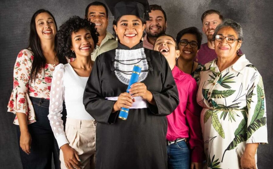 Formando de primeira geração segurando diploma, simbolizando ascensão salarial após faculdade particular