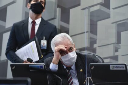 Senador Flávio Bolsonaro em destaque com bandeiras do Brasil e EUA ao fundo, representando crise institucional e risco país