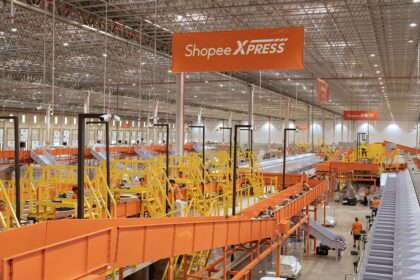 Centro de distribuição Shopee com esteiras transportadoras e pacotes laranja, simbolizando expansão logística de 60% no Brasil