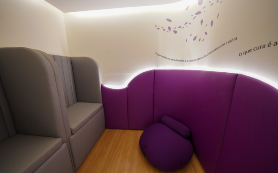 Sala sensorial em shopping com iluminação suave, puffs coloridos e painéis interativos para autistas