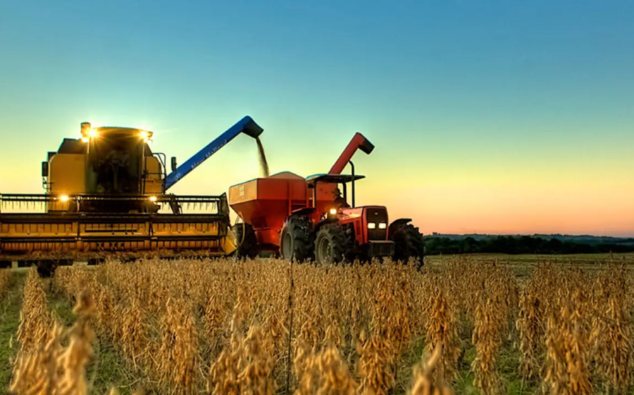 Plantação de soja extensiva no Brasil com máquinas agrícolas colhendo grãos