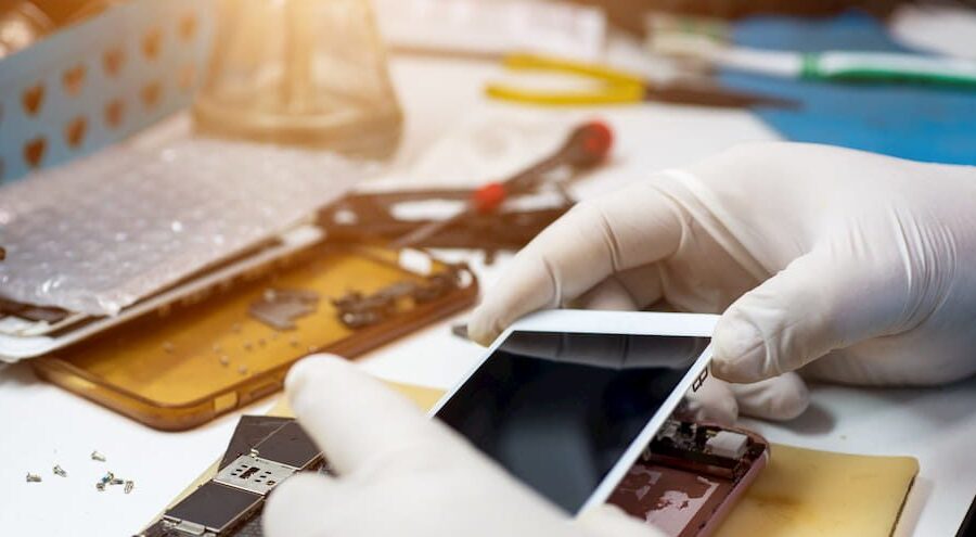 Técnico de assistência técnica acessando dados privados em smartphone durante reparo
