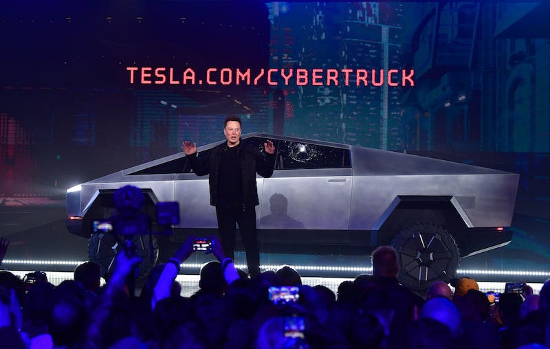 Elon Musk sorri ao lado de um Tesla Model 3 com gráfico de ações em alta ao fundo