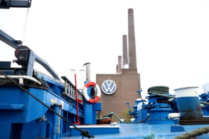 Funcionários da Volkswagen em linha de montagem com gráficos de salários congelados até 2030