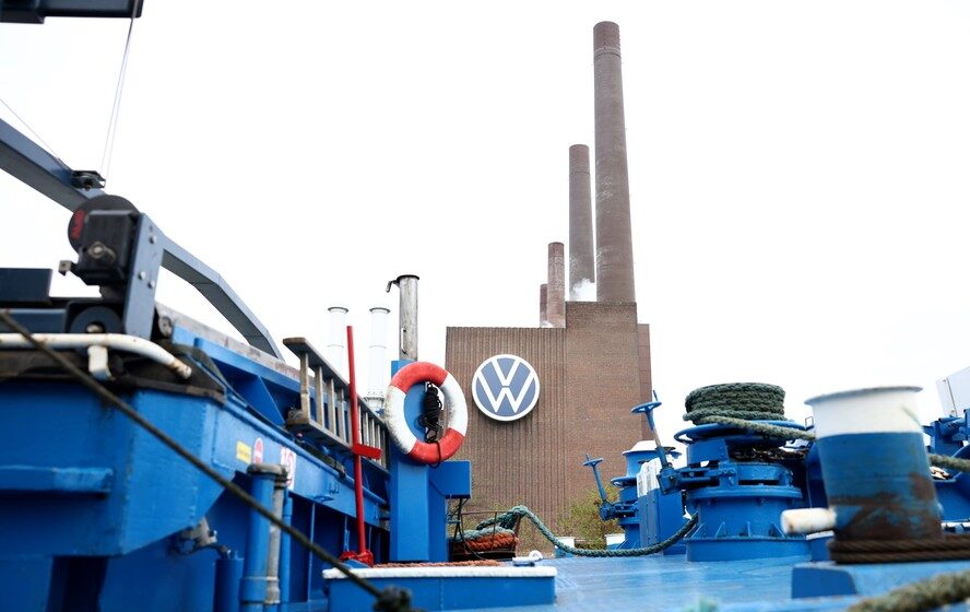 Funcionários da Volkswagen em linha de montagem com gráficos de salários congelados até 2030